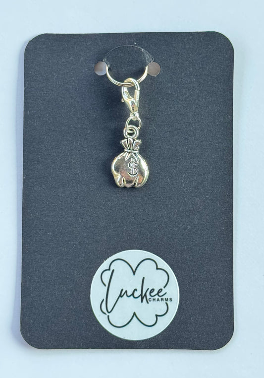 Silver money bag charm on a black card with 'Luckee Charms' branding.