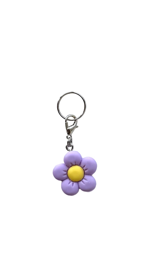 Flower-shaped charm with a purple petal and yellow center on a white  background