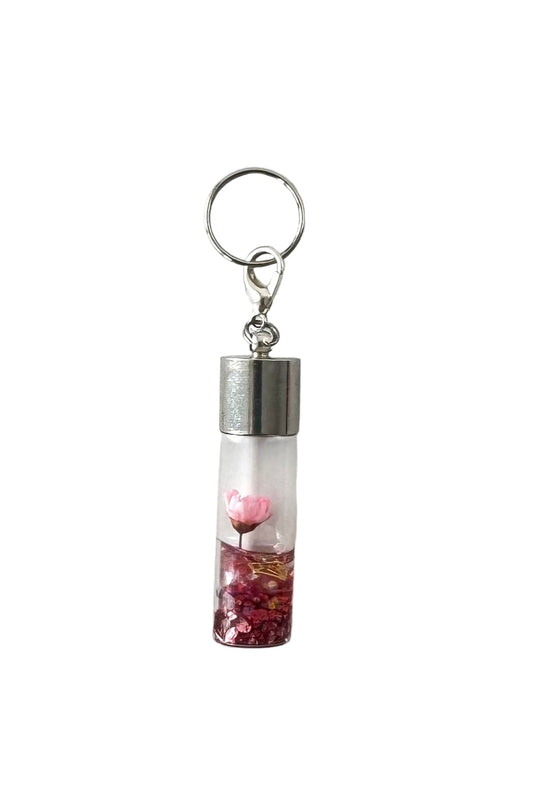 Charm with a clear tube containing pink heart-shaped objects on a white background