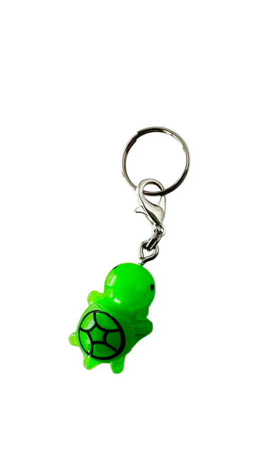 Green turtle charm with a black circle on a white background