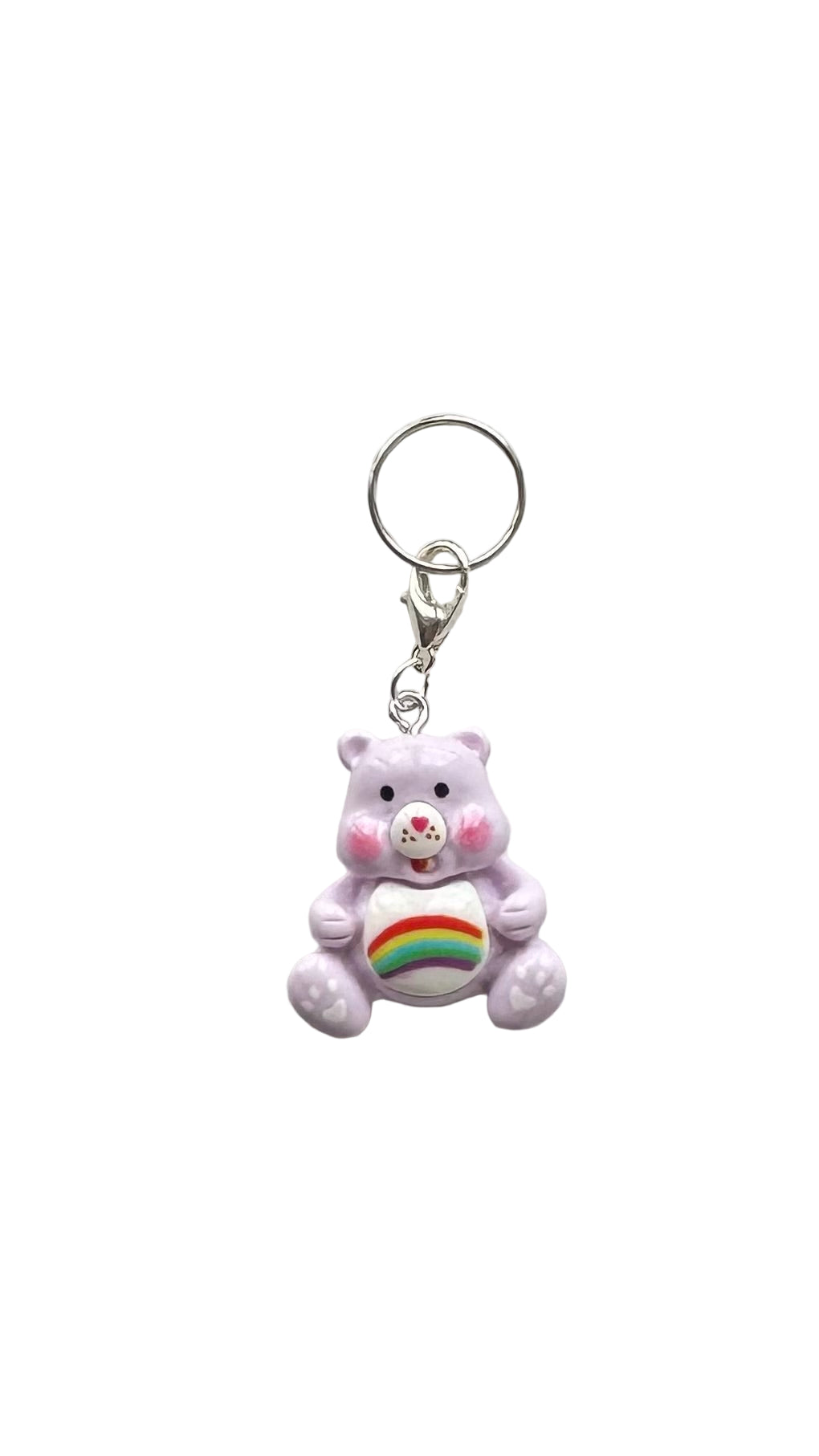 Purple teddy bear charm with a rainbow heart on a white background