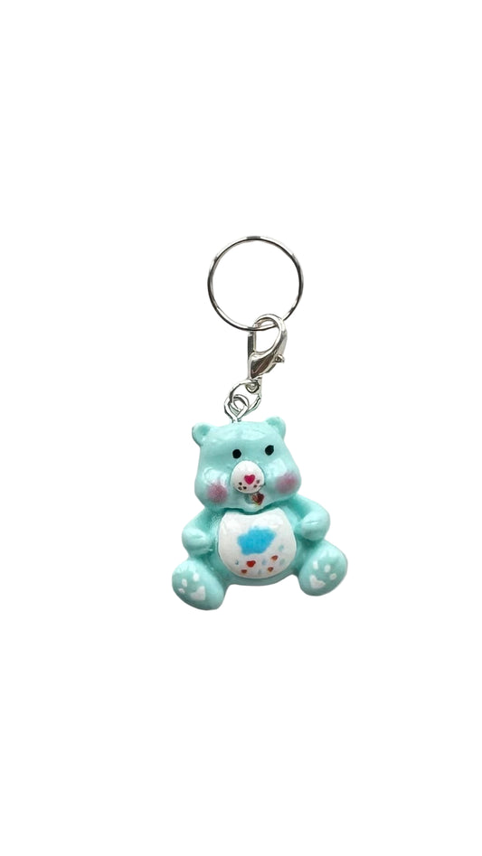 Blue teddy bear charm with a rain cloud on a white background