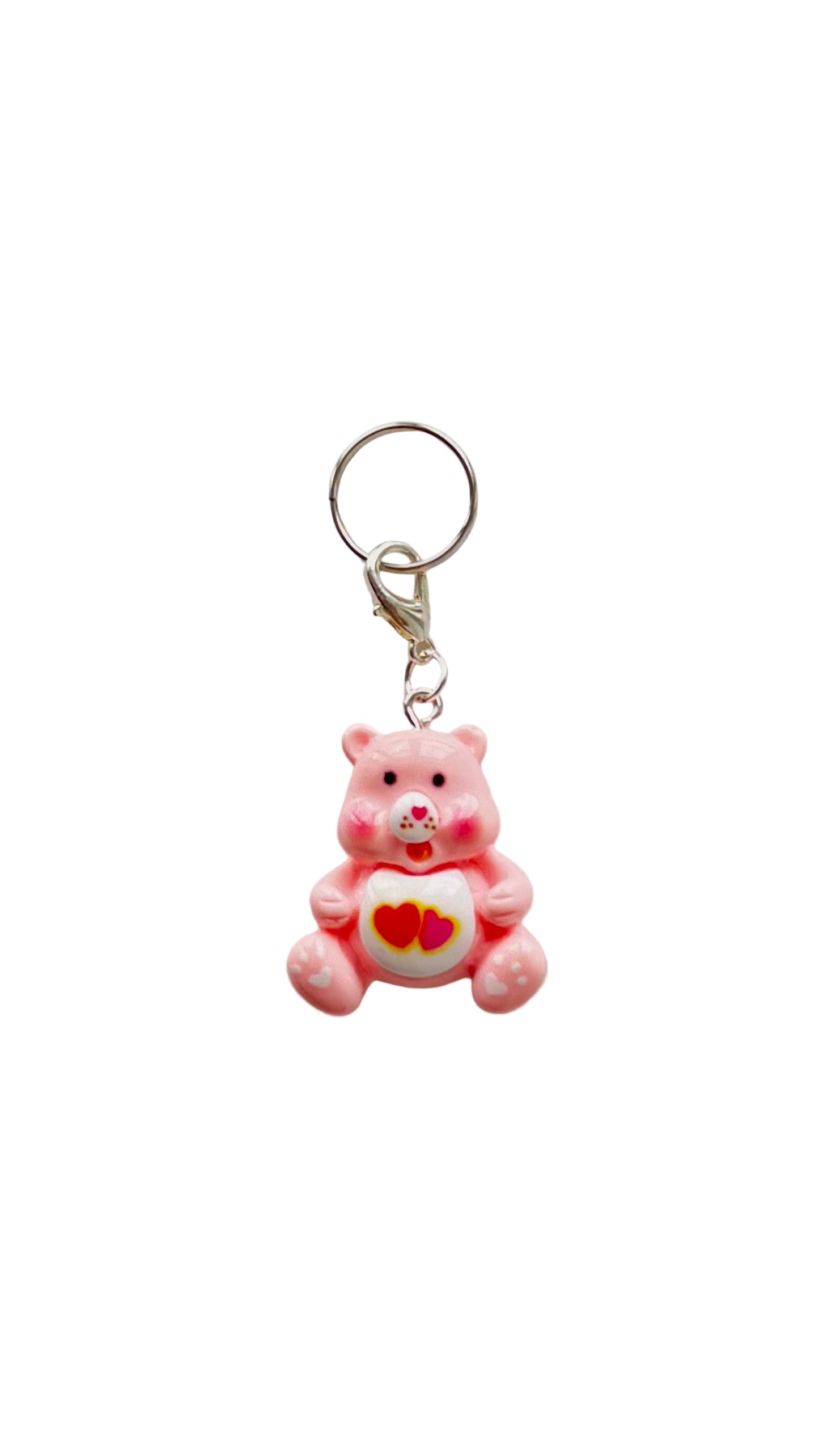 Pink teddy bear charm with a heart on a white background