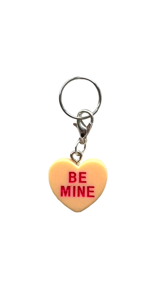 Heart-shaped charm with 'BE MINE' text on a white background