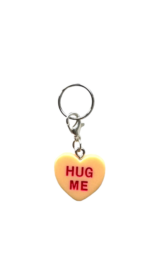 Heart-shaped charm with 'HUG ME' text on a white background