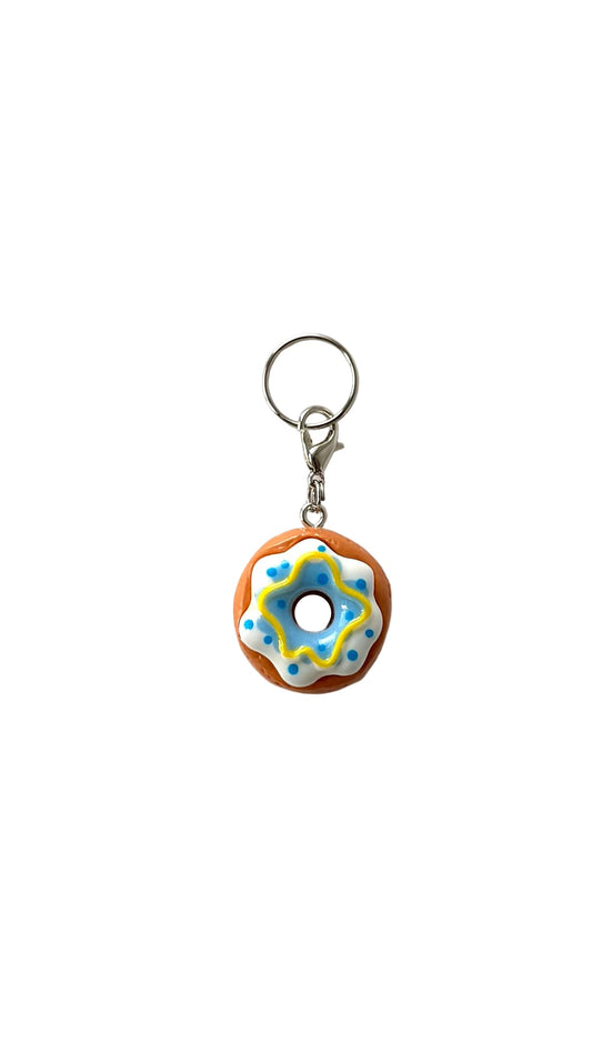 Donut-shaped charm with colorful icing on a white background