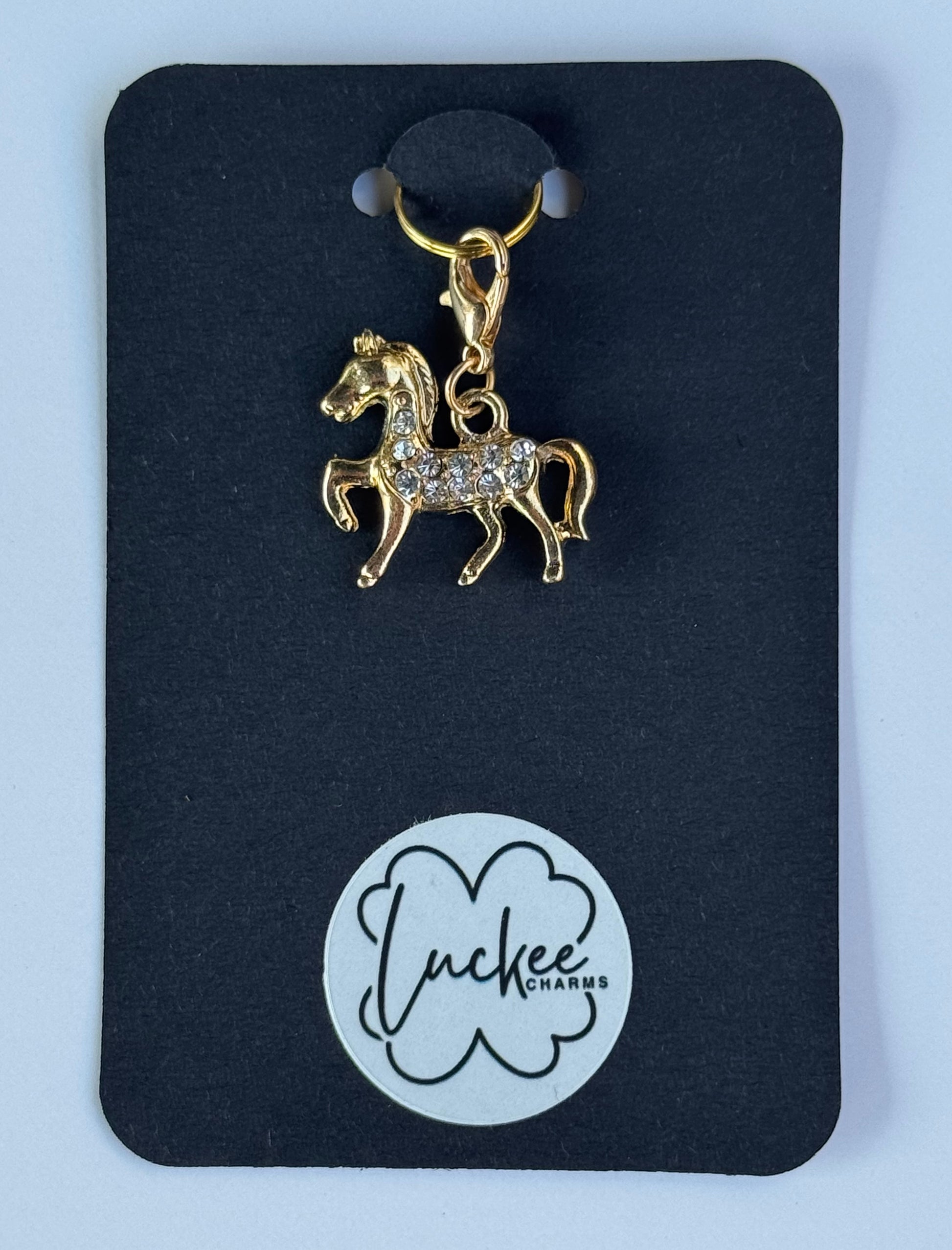 Gold horse-shaped charm on a black card with 'Luckee Charms' branding.