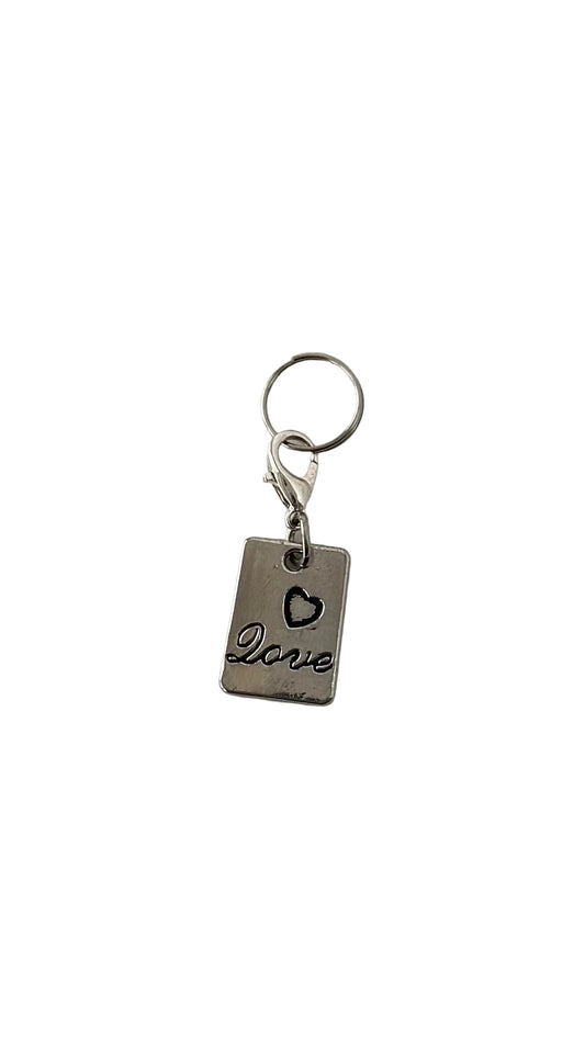 Silver charm with 'love' and heart charm on a white background