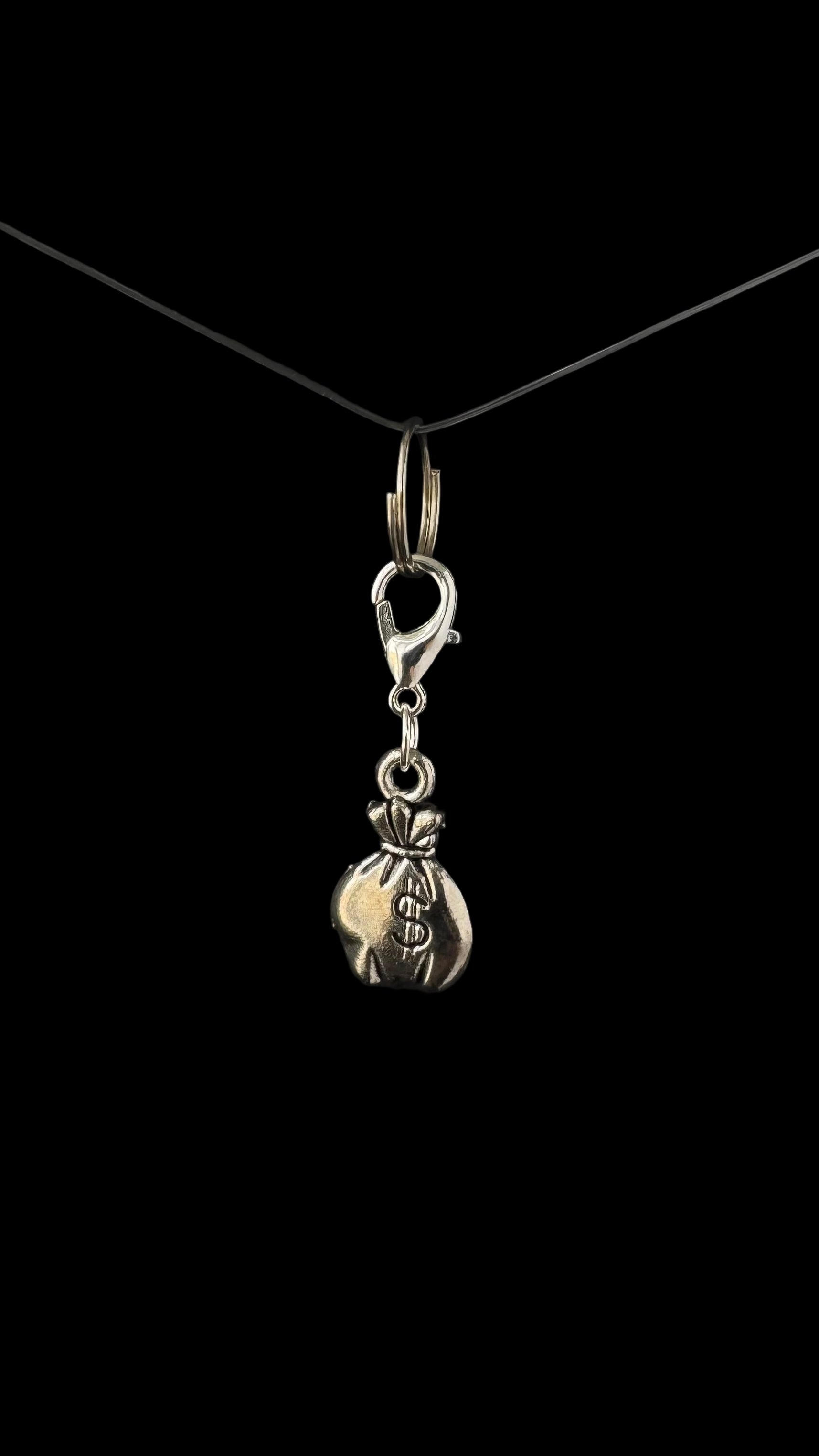 Silver money bag charm on a black background.