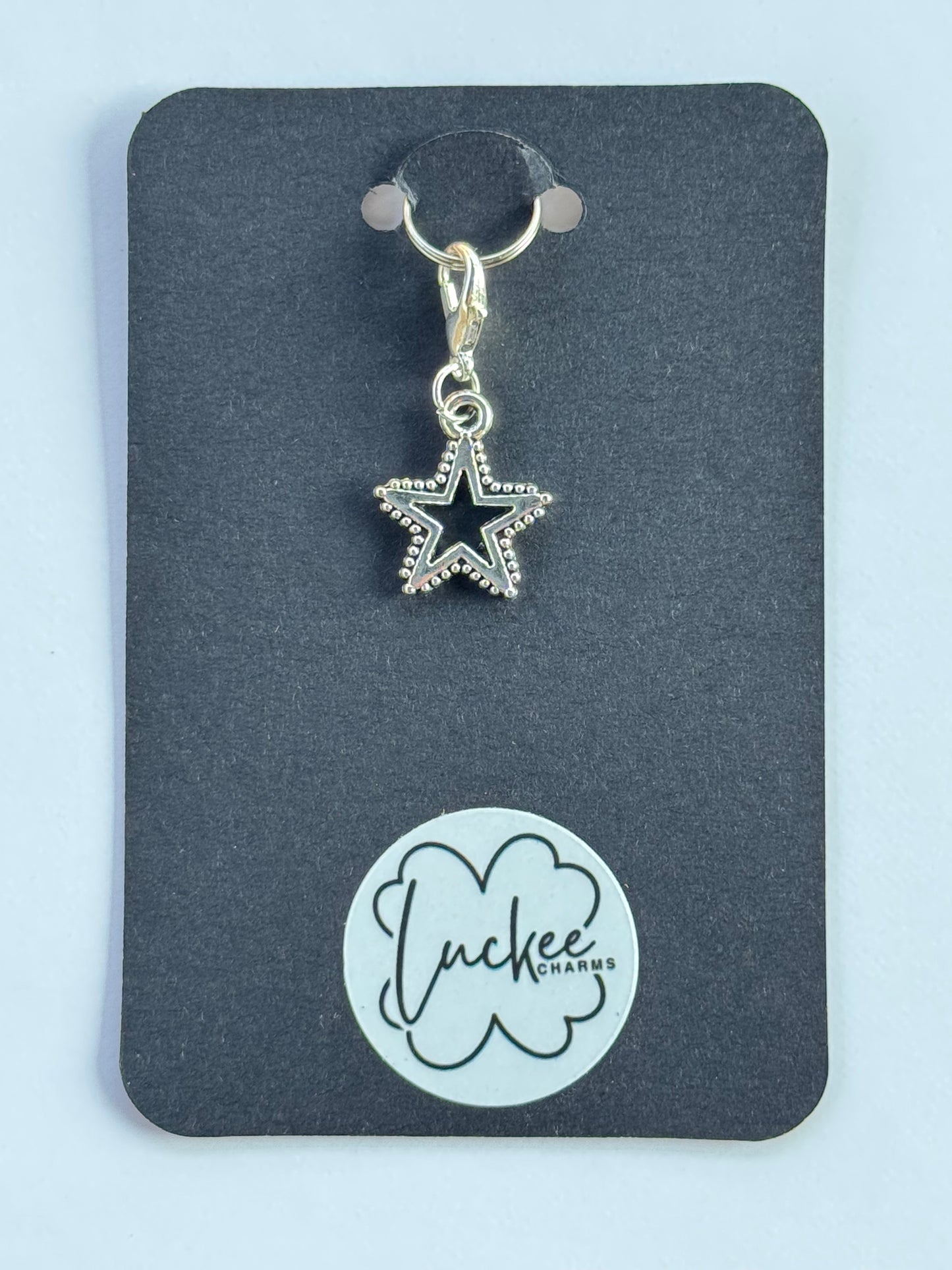Star-shaped charm on a black card with a brand logo.