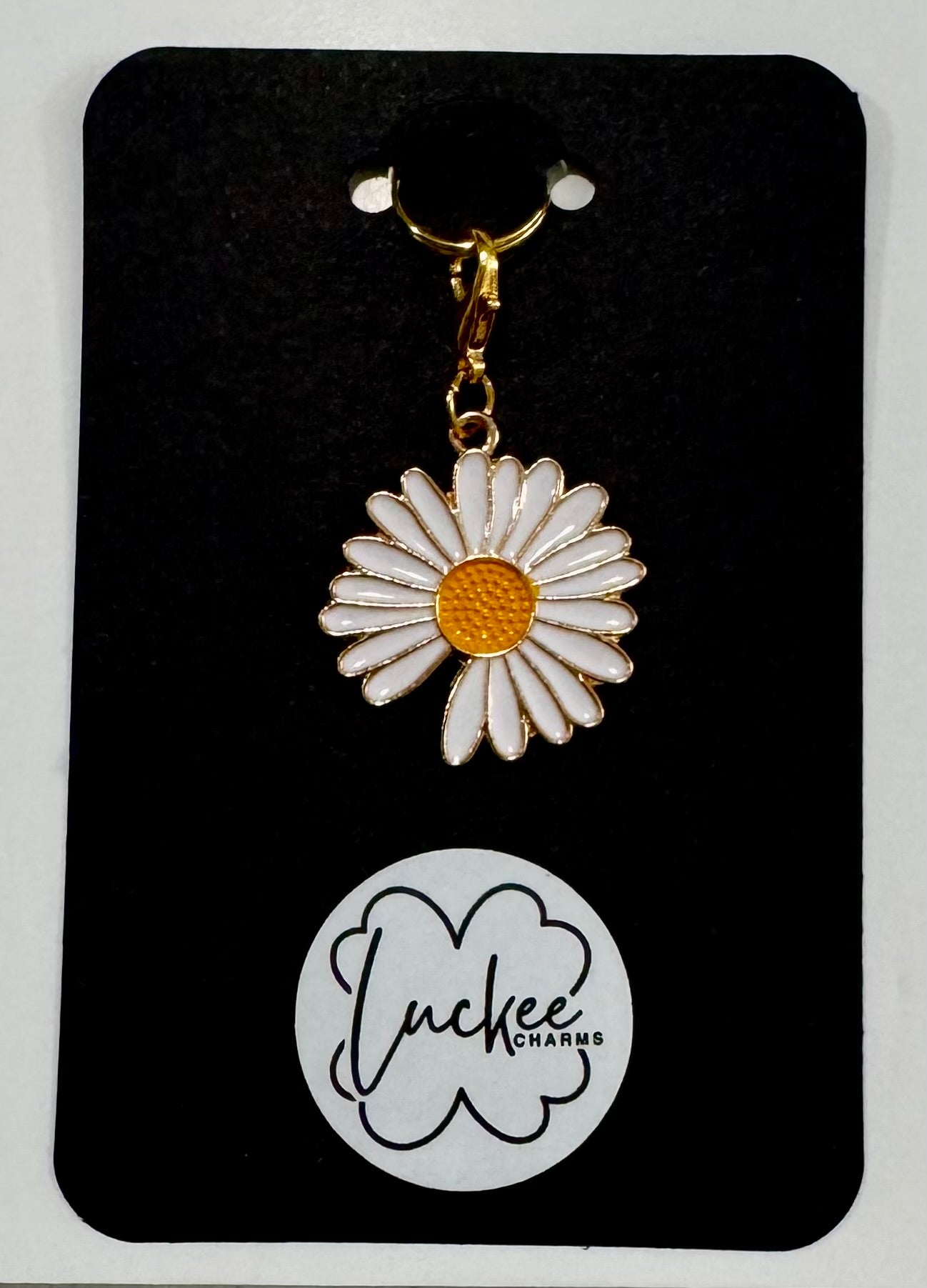 Daisy-shaped charm on a branded card.