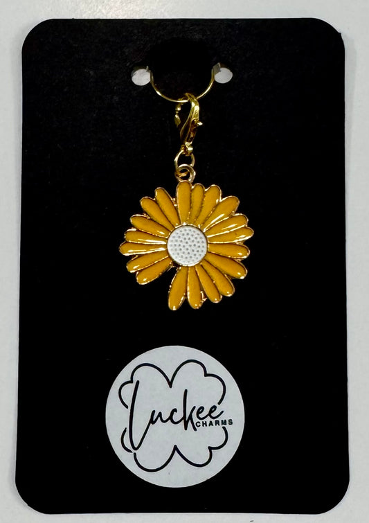Yellow daisy-shaped charm on a black card with 'Luckee Charms' branding.