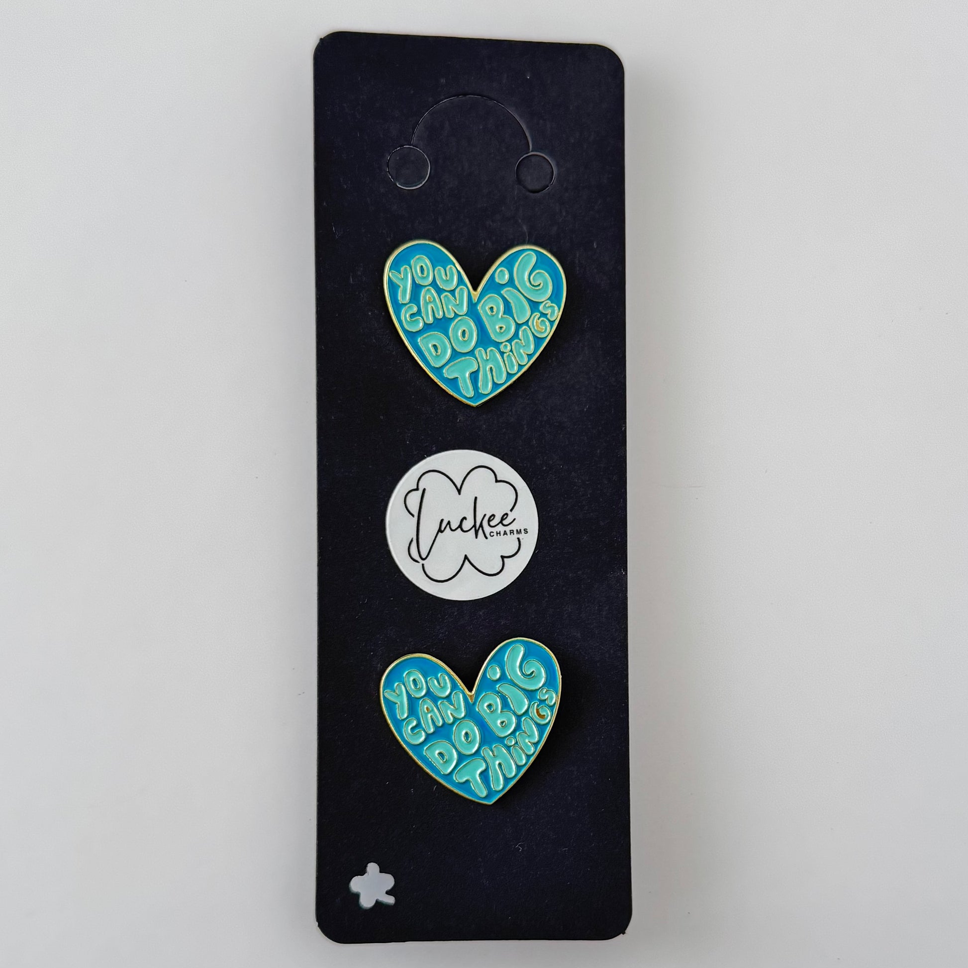 Two blue heart-shaped pins with text on a black card, featuring the brand 'Jockey'.