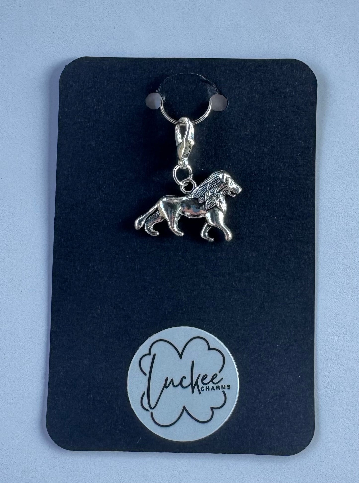 Silver lion charm on a black background. 