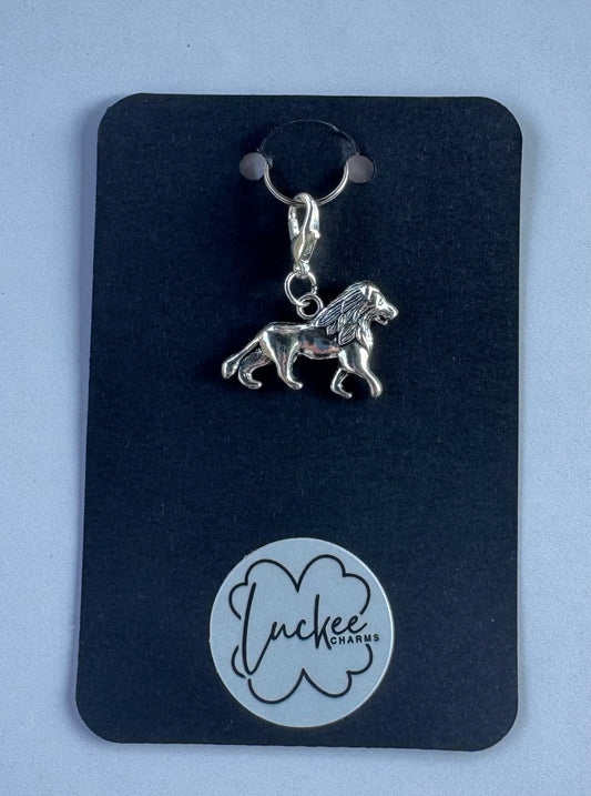 Silver lion charm on a black background. 